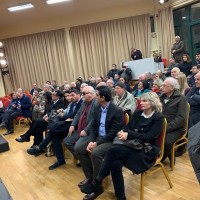 Ο Ι. Βαρδακαστάνης καθισμένος στην αίθουσα εκδηλώσεων ανάμεσα σε πλήθος κόσμου